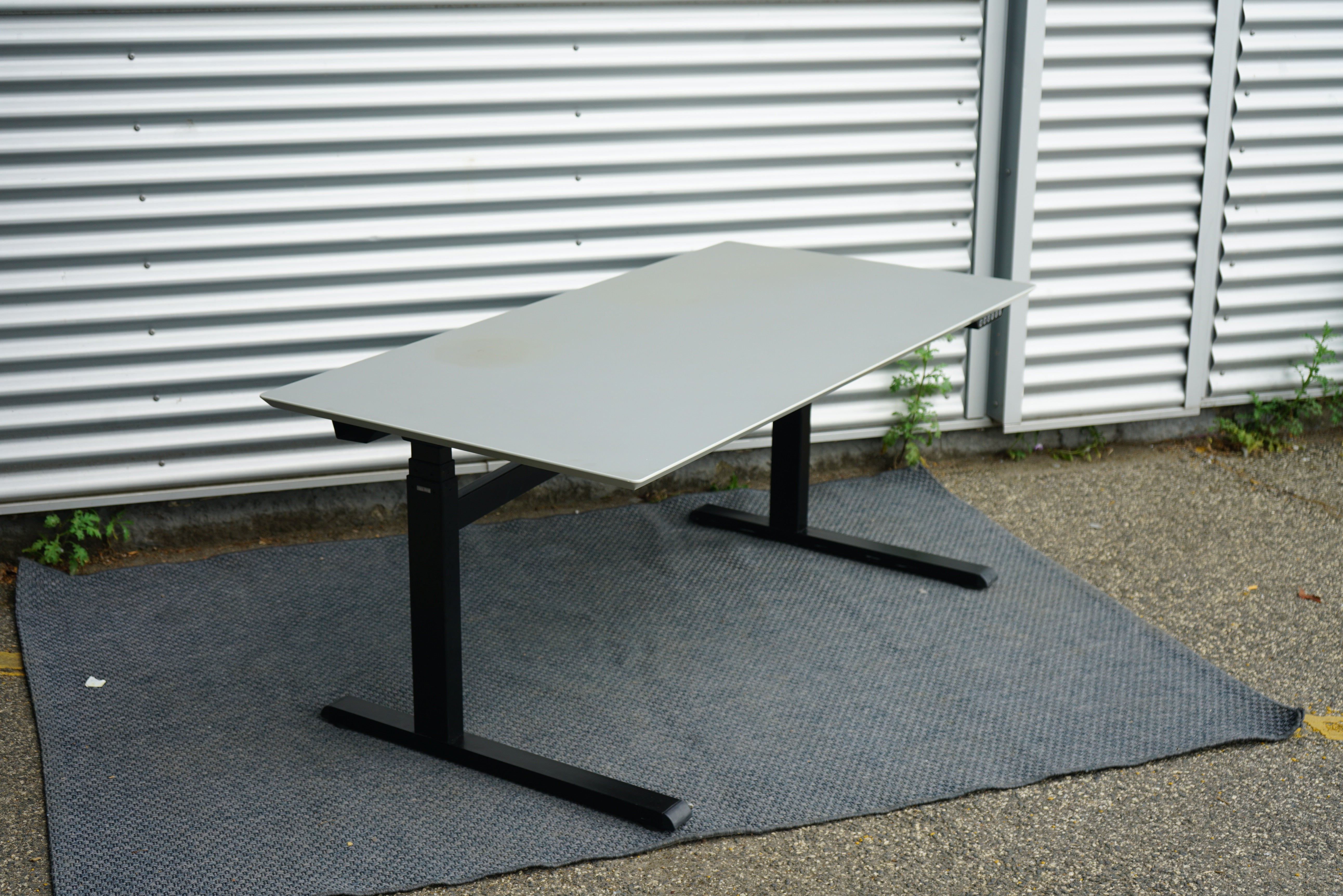 Duba B8 hæve-sænkebord 160x80 cm i lysegrå linoleum set fra skrå vinkel med affasede kanter og kabelbakke